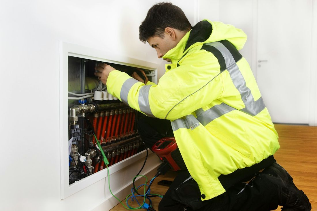 Engineer diagnosing an underfloor heating manifold