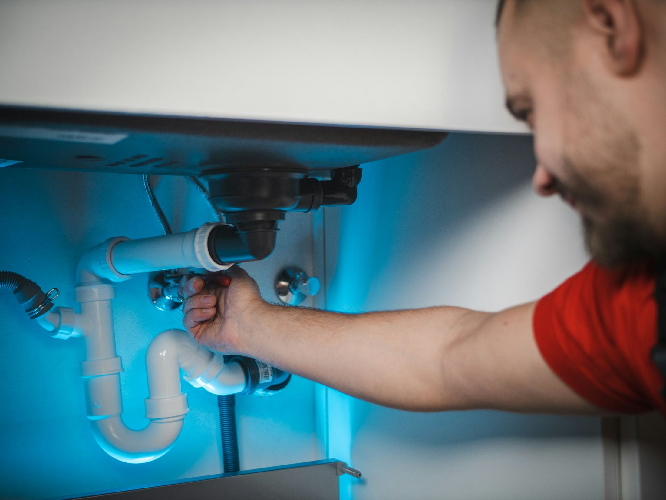 PH247 engineer repairing pipework under a sink