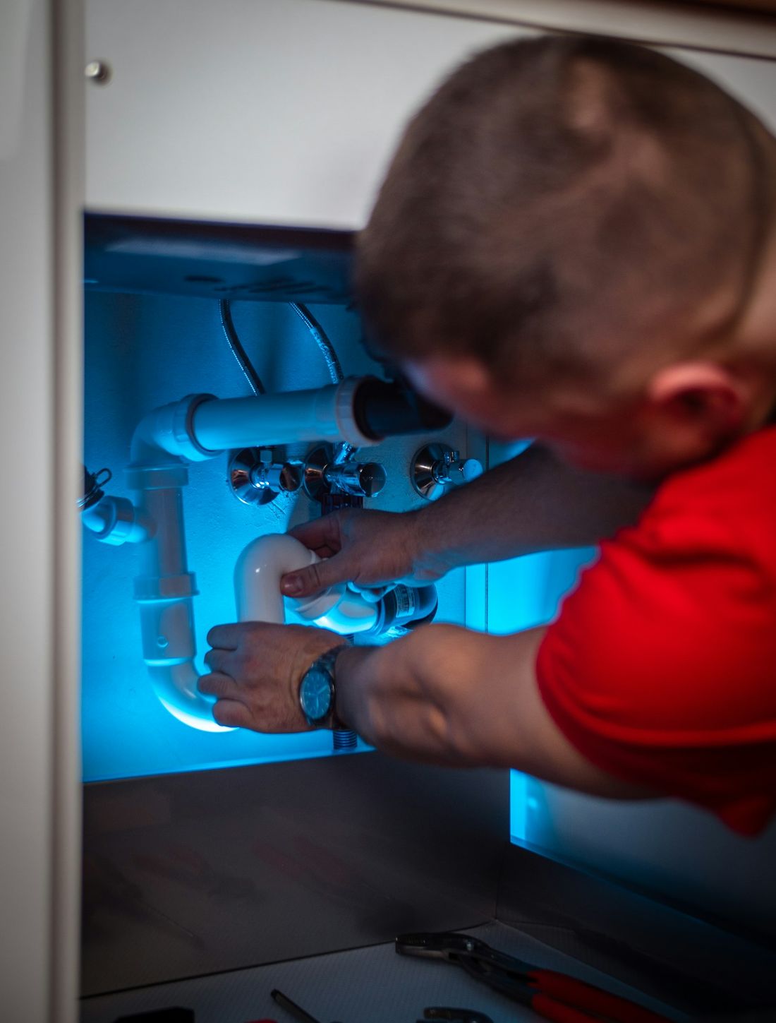 PH247 engineer fitting new pipework under a kitchen sink